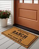 Welcome to Our Ranch Coir Doormat on a wooden floor in front of a brown door.