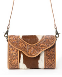 Brown and white cowhide handbag with leather accents on a white background