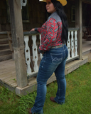 Woman in a patterned shirt and jeans standing on a wooden porch.