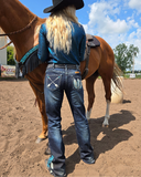 Person in cowboy hat and jeans standing next to a horse in an outdoor setting