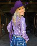 Woman wearing a purple leopard top and cowboy hat in a barn setting