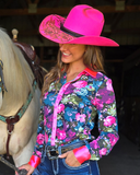 Woman in a colorful floral shirt and pink cowboy hat standing next to a horse.