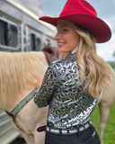 Woman in a patterned shirt and red hat standing next to a horse