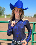 Woman wearing a blue glitter shirt and cowboy hat in an outdoor setting