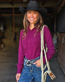 Woman in a burgundy shirt and cowboy hat holding a rope halter in a barn setting