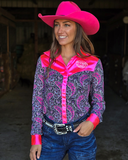 Woman wearing a pink and navy paisley patterned shirt with a cowboy hat in an indoor setting