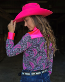 Woman wearing a pink cowboy hat and a patterned shirt with a dark background