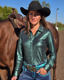 Woman in a sparkly green shirt and cowboy hat standing next to a horse.