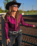Woman in a magenta shirt and black cowboy hat standing in an outdoor setting