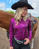 Woman wearing a pink patterned shirt and black cowboy hat with a horse in the background