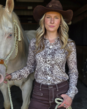 Woman wearing a brown and cream lace shirt standing next to a horse.