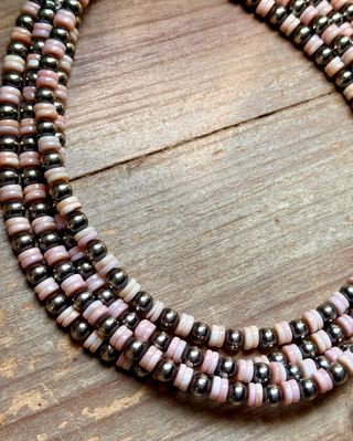 Beaded necklace with pink and silver beads on a wooden surface