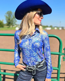 Woman wearing a blue iridescent shirt and cowboy hat in an outdoor setting