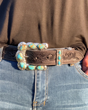 Person wearing blue jeans with a decorative belt featuring a large buckle.