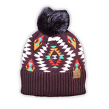 The Aztec Pom Beanie in a white back drop.