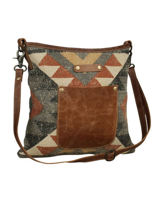 Patterned handbag with brown leather pocket on a white background