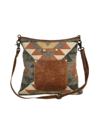 Crossbody bag with geometric pattern and brown leather pocket on a white background