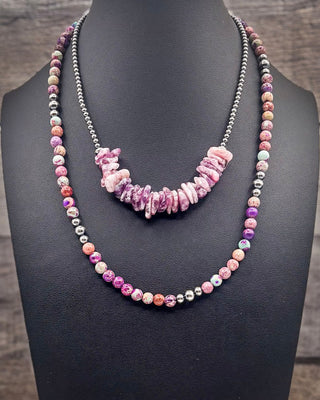 A double-strand necklace displayed on a black jewelry bust. One strand features polished pink and purple stone beads with small silver spacer beads, while the other strand has a central cluster of irregular pink stone chips flanked by silver-toned beads.