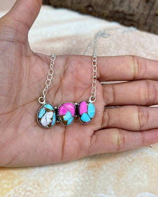 Necklace with colorful stones held in a hand on a textured surface
