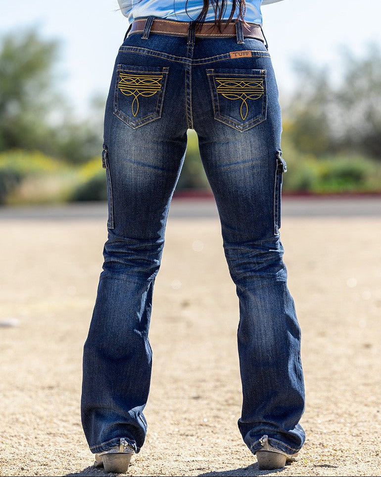 Person wearing blue jeans with decorative stitching on a blurred outdoor background