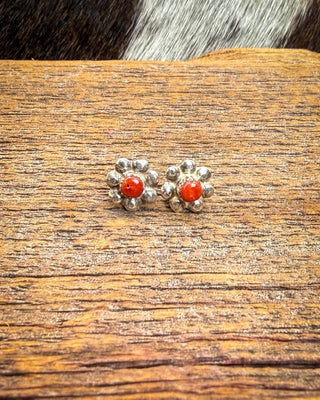 Coral and sterling silver flower earrings by Ronald Yatsattie, shown as a pair on rustic wood