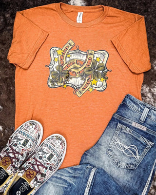 You know that in-between weather where it’s almost sweater season, but you’re still clingin’ to short sleeves? This tee’s made for exactly that. 🍂

The Lucky Stars Graphic Tee has soft, cozy, and fall-in-a-shirt energy.

That warm harvest orange? Perfect with denim. The horseshoe + clover graphic? A lil’ lucky charm to carry you through the season.

And the cherry on top? It’s on sale. 😘