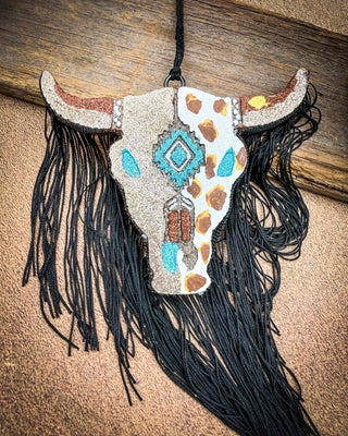 Brown, turquoise and gold car freshie laying on wood