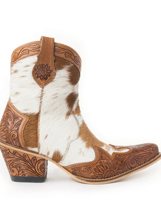 A single women's western ankle boot with a brown and white cowhide pattern, hand-tooled leather detailing, and a stacked block heel, shown against a plain white background.