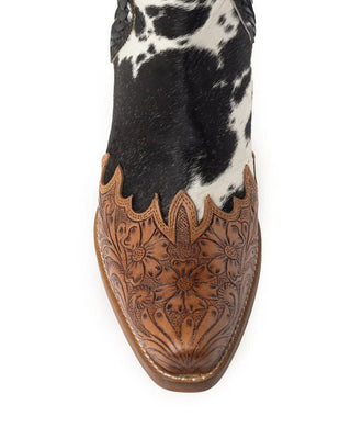A single cowboy boot shown from the side against a white background, featuring a black and white cowhide shaft and a brown tooled leather vamp with floral detailing.