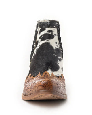 Cowhide patterned boot with brown leather sole on a white background