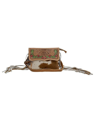 A small brown leather crossbody bag with fringe, featuring a flap decorated with a sunburst pattern and colorful floral embroidery, and a cowhide patch on the front, shown against a plain white background.