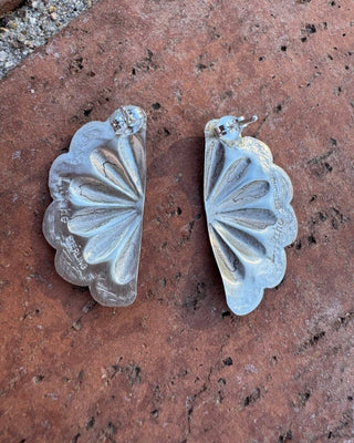 Silver floral earrings on a textured brown surface