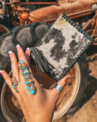 Hand holding a cowhide wallet with vintage tractor in background