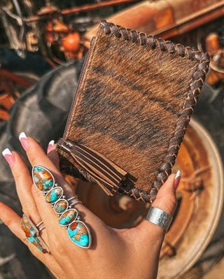 Hand holding a leather card wallet with vintage tractor in background