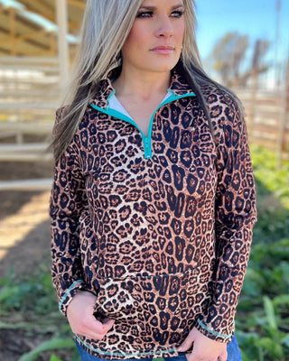 Woman wearing a leopard print pullover with turquoise lining outdoors.