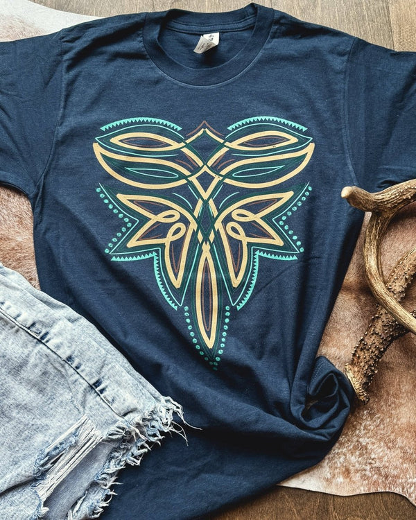 Navy blue t-shirt with a decorative emblem on a wooden surface with denim shorts and antlers.