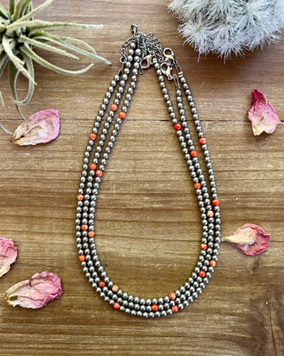 Necklace with beads on a wooden surface with dried flowers and plants