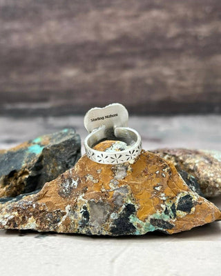 Silver ring with a heart-shaped tag on a rock