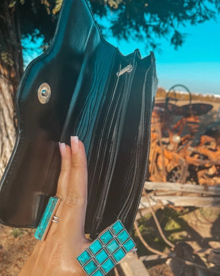Black wallet held by a hand against a natural background