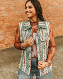 Woman wearing a patterned vest against a brick wall