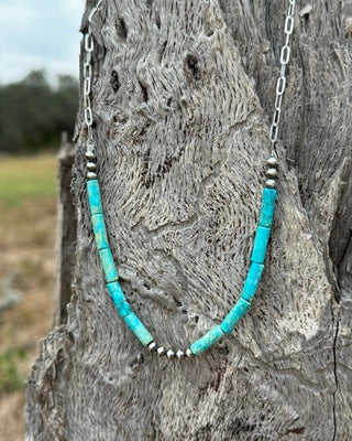 Turquoise beaded necklace on a wooden post with a natural background