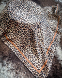 The Liberty Leopard Wild Rag draped over a wooden cable reel and cowhide.