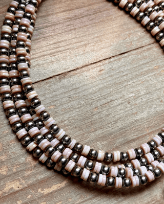 Beaded necklace with pink and silver beads on a wooden surface