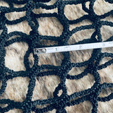 Black knitted mesh with a measuring tape indicating dimensions on a wooden surface