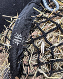 Black hay net with a carabiner on a background of straw and hay.