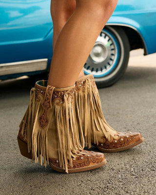 Person wearing fringed boots standing in front of a blue classic car.