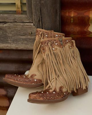 Pair of brown fringe boots with detailed designs on a rustic background