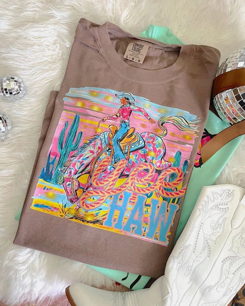 Brown t-shirt with colorful graphic design on a fluffy white surface