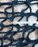 Black rope netting with a ruler for scale on a wooden surface