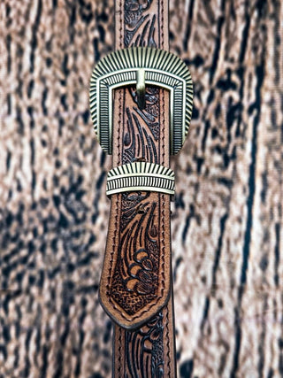 Close-up of tooled leather belt with engraved western-style brass buckle